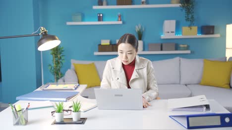 Asian-woman-hurriedly-sits-in-front-of-laptop-from-outside-and-gets-to-work.
